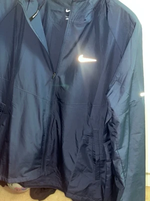 Mörkblå Nike vindjacka med huva - Nike miler vindjacka med kvitto .