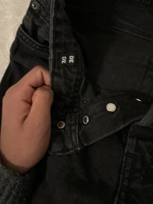 Svarta wide jeans från Jack & Jones - Svarta jeans från Jack & Jones, modell Relaxed/Chris. De har en bred passform med raka ben och klassisk knappgylf. Materialet är jeans och färgen är mörk svart. Perfekt för dig som gillar avslappnad stil och vill ha lite extra utrymme i benen.