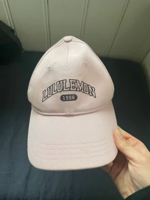Keps - Bilden visar en ljusrosa keps från Lululemon med broderad text!