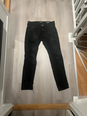 Replay svarta jeans, storlek 30/32 - Svarta Replay jeans i slim fit med klassisk femficksdesign och knappstängning. Jeansen har en smal siluett och är tillverkade i stretchig bomull för skön passform. Perfekta för dig som gillar stilrena och moderna jeans.