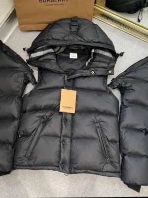 Svart dunväst från Burberry med huva - Säljer en svart dunväst från Burberry med avtagbar huva och klassiskt rutigt foder. Västen har två snedställda fickor med dragkedja, knappar framtill och en Burberry London England patch på bröstet. Perfekt för lager-på-lager och riktigt snygg till streetwear.