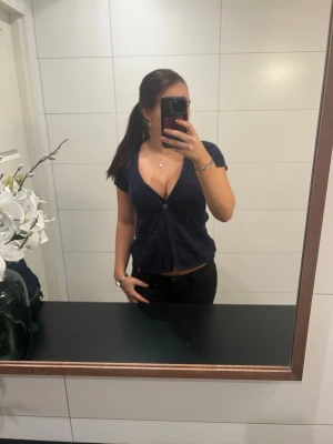 Mörkblå v-ringad topp från edc - Säljer en mörkblå v-ringad kofta från edc i storlek S. Kofta har korta ärmar, knappar framtill och en croppad passform. 