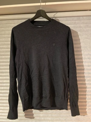 Mörkblå/grå stickad tröja Jack & Jones - Svart stickad tröja från Jack & Jones Premium, Modern Archive. Tillverkad i ekologisk bomull och kashmir, med rund hals och ribbade muddar. Okej skick! Storlek XS. //David