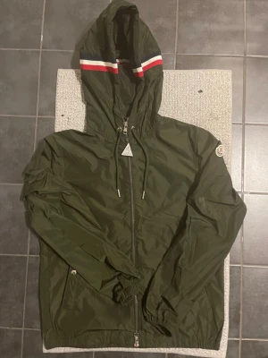 Moncler Windbreaker - Snygg olivgrön vindjacka från Moncler med huva🫒 Perfekt för hela året❄️🍃☀️🍁Den har en liten defekt på ärmen som jag har lagat och är veldigt osynligt. Det kan du se på sista bilden. Storleken är 1 vilket motsvarar  S i svenska storlekar. Skriv vid funderingar🧩