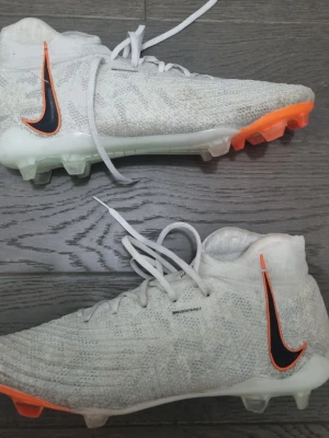 Nike phantom luna vit orange fotbollskor - Det här är en sko med äldre modell så väldigt svårt o få tag på de hade jag anat,De är använda under en liten period o det syns inget slitage förutom att det är lite smutsfläckae man kan få bort med gnuggning , Skorna är stora i storlek så jag hade rekomderat att om man har breda fötter de är storlek 43 men passar 44 eftersom den modellens storlek. Priset kan diskuteras.