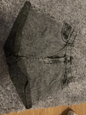Grå högmidjade shorts från New Yorker - Säljer ett par gråa denimshorts från New Yorker i storlek M. De är högmidjade med resår i midjan, har två fickor bak och klassiska jeanssömmar. Perfekt för dig som gillar en chill och snygg stil.