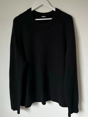 Svart stickad tröja från Arket XL - Svart stickad tröja från Arket i storlek XL. Tröjan har rund halsringning och långa ärmar med ribbade muddar. Enkel och stilren design som funkar till många olika looks. Perfekt för kyliga dagar och enkel att matcha med jeans eller chinos. 5M3