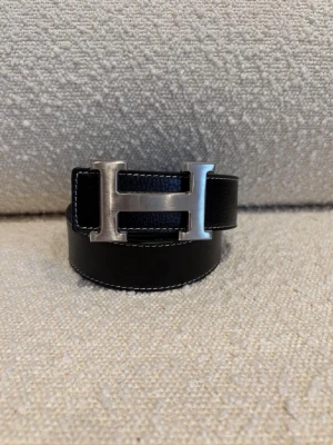 H-bälte - Ett svart H-bälte perfekt för dig som gillar mode och stil, bältet har ett H med färgen silver och är ett fint märke och ett välkänt märke från Frankrike Paris. Kom dm för eventuella frågor 🧐pris kan diskuteras 💯. 
