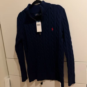 Ralph Lauren - Säljer en helt ny marinblå POLO RALPH LAUREN kabelstickad tröja i storlek S, aldrig använd med prislapp kvar. Perfekt för alla tillfällen! Hör av dig vid intresse.
