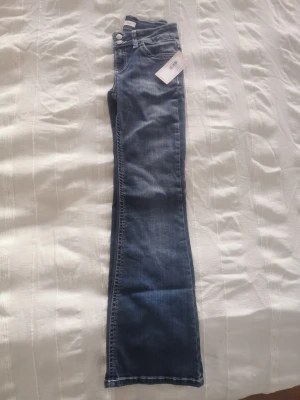 Bootcut jeans mörkblå NLY 34/Short - Helt nya jeans, endast testade en gång! Mörkblå bootcut jeans från NLY med låg midja och snygga vita sömmar på bakfickorna. Modellen har klassisk femficksdesign och är tillverkad i mjukt jeansmaterial. Perfekt för dig som gillar retrovibbar och vill ha en cool siluett.