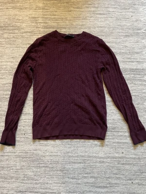 Vinröd kabelstickad tröja - Snygg vinröd kabelstickad tröja med rund hals och långärmad. Fint skick, storlek S