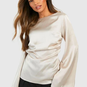 Champagnefärgad satinblus med vida ärmar - Måste tyvärr sälja denna snygga champagnefärgad blus från boohoo i glansig satin då den var för liten för mig, Blusen har vida långärmar, rund halsringning och snygg rynkning i midjan baktill. den är helt ny med prislapp kvar💕. Bilderna har inte rättvist ljus