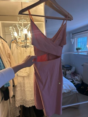 Rosa omlottklänning med cut-out - Säljer en rosa kortklänning med omlottdetalj och cut-out vid midjan. 