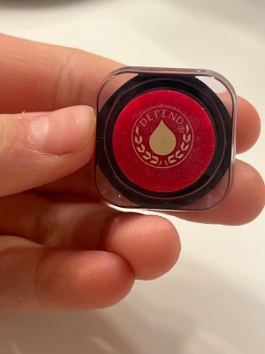 Rött läppglans från Depend - Säljer ett rött läppglans från Depend i en liten rund plastburk. 