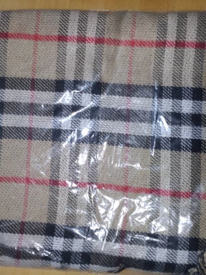 Halsduk  - Säljer en klassisk rutig halsduk i beige, svart, vit och röd. Den är oanvänd och aldrig uppackad från påsen. 