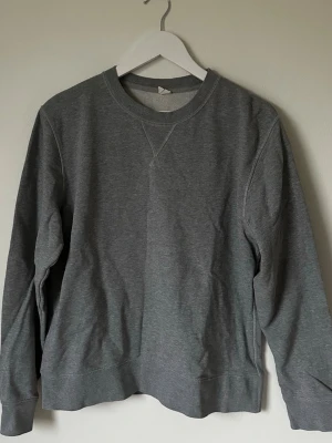 Grå sweatshirt från ARKET, M - Säljer en enkel och stilren grå sweatshirt från ARKET i storlek M. Tröjan har rund hals, långa ärmar och ribbade muddar vid ärmslut och nederkant. Perfekt för chill dagar och passar till allt. Materialet är mjuk bomull som känns skönt mot huden. 6Q5