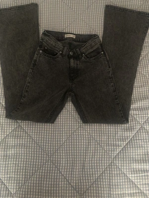 Svarta bootcut jeans från Perfect Jeans - Säljer ett par svarta bootcut jeans från Gina. Tricot i storlek 32. Jeansen har klassisk femficksdesign, knapp och dragkedja fram samt en snygg tvättad look. Materialet är jeans och passformen är normal med lite vidare ben nertill.passar perfekt till dig som har lite mindre lår. Inga returneringar.