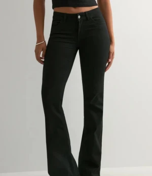 Svarta bootcut jeans med låg midja - ( Helt oanvända och nya, de är till och med kvar i besstälnings förpackning)   Orginalpris 699kr                               Snygga svarta jeans med bootcut-ben och låg midja. Klassisk femficksmodell med dragkedja och knapp framtill. Jeansen har en stilren look och är tillverkade i ett stretchigt jeansmaterial som sitter bekvämt. Perfekta för dig som gillar en tidlös och cool stil.