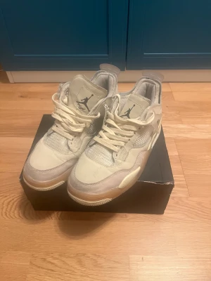 Nike Air Jordan 4 Off-White Sail - Säljer ett par Nike Air Jordan 4 Off-White Sail sneakers i en ljusbeige färg. Skorna har meshpaneler, detaljer i syntet och skinn samt tydliga Off-White-signaturer som 'AIR'-texten på sulan. Klassisk snörning och ikonisk Jumpman-logga på plösen.