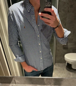 Rutig blåvit skjorta från Ralph Lauren - Säljer en klassisk rutig skjorta från Ralph Lauren i blått och vitt. Skjurtan är i riktigt bra skick utan några defekter. Jag på bilden är 188cm och bör storlek M. Hör av er vid frågor:)