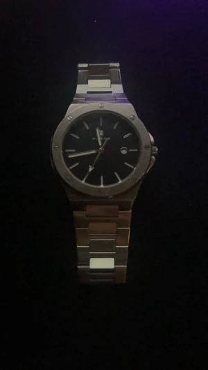 Silverfärgad klocka - Stilren klocka från Black Oak med svart urtavla och datumvisning. Armbandet är i silverfärgat metall och har en klassisk länkdesign. Urtavlan är rund med minimalistiska markeringar och boetten har synliga skruvar för en modern touch. OBS den är ganska stor på min arm, är en medelviktig person! Men det är länkar på den som är lätt borttagna så de är inget problem! Kvitto finns!