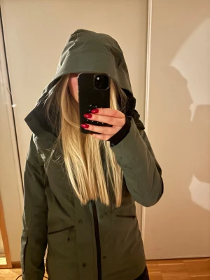 Skidjacka - Snygg grön skidjacka med huva och dragkedja framtill. Jackan har två fickor med dragkedja och en stilren, minimalistisk look. Perfekt för dig som gillar funktionella och stilrena ytterplagg. Jackan är långärmad och har en rak passform. Intressekoll på denna snygga skidjacka! Använd men jättebra skick💕