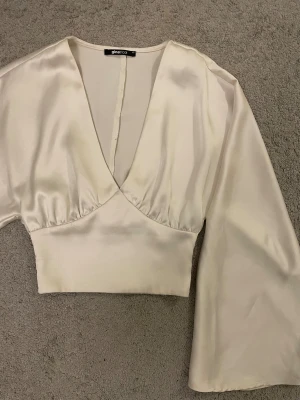 Vitt topp med vida armar från Gina tricot - Vit festtopp i storlek XS, den är dock väldigt stor så jag skulle säga att det passar till och med en M. Resorband i ryggen och stora/vida armar