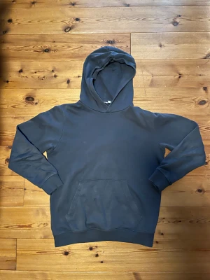 Mörkblå Hoodie Kappahl - En snygg mörkblå hoodie från Kappahl. Passformen är väldigt bra och tyget är hyfsat tunt. Den är i väldigt bra skick och bara använd ett fåtal gånger. Inga fläckar eller skador. Den är av 87% bomull och 13% polyester.       Armlängd: 58 cm                                 Längd: 65 cm                                       Midjemått: 45 cm                               Säljer eftersom den inte passar mig längre.
