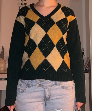 Rutig v-ringad tröja i mörkgrönt och gult - Snygg v-ringad tröja med klassiskt rutmönster i mörkgrönt, gult och beige. Tröjan har långa ärmar och ribbade muddar vid ärmslut och nederkant. Skriv för fler bilder🫶
