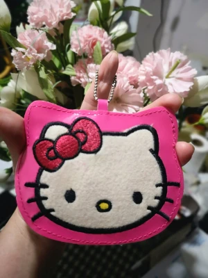 Hello Kitty Hängare  - Mått 10,5*9cm Helt ny. En liten söt utsmyckning att hänga på jacka, ryggsäck, barnvagn eller väska...en lite ficka på baksidan.