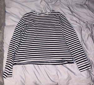 Randig långärmad tröja  - Snygg långärmad tröja med klassiskt svartvitt randigt mönster. Tröjan har en rund halsringning och är tillverkad i mjuk bomull, perfekt för dig som gillar enkel och stilren design. Passar dig som vill ha en chill och clean look.