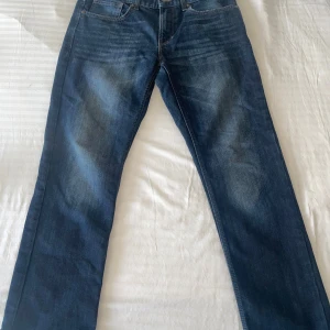 Blå straight jeans från C&A, 34/34 - Säljer ett par klassiska blå jeans från C&A i modellen The Straight. Jeansen har raka ben, fem fickor och snygga slitningar framtill. Perfekt passform med normal midja och cool tvättad look. Materialet är tåligt denim som håller länge.
