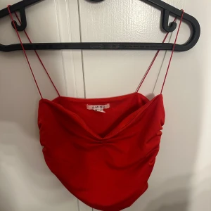 Röd linnetopp med tunna axelband Amisu - Snygg röd linnetopp från Amisu med tunna axelband och draperad framsida. Toppen har en croppad passform och är tillverkad i ett mjukt, stretchigt material som sitter bekvämt. Perfekt för dig som vill sticka ut med en enkel men trendig look.