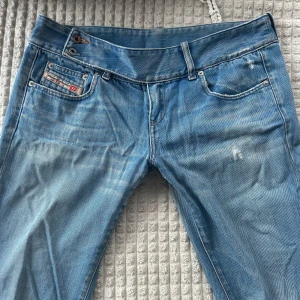 Ljusblå jeans från Diesel - Säljer ett par ljusblå bootcut jeans från Diesel, köpta på en vintage butik i London för 1500kr! Säljer dem då de tyvärr inte längre kommer till användning. Det finns en knapp som saknas (se bild), men det är något man lätt kan fixa😊Passar mig hur bra som helst som är 175cm lång! De är även lowwaist i modellen💞Pris kan diskuteras! 