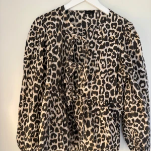 Leopardmönstrad blus från Qnuz - Säljer en leopardmönstrad blus från Onuz med puffiga långärmar som går att kavla upp till trekvart!! Blusen har rosett snörningsdetaljer framtill. Den är i one size sitter perfekt på mig som bär S. Nypris 600