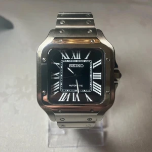 Seiko Santos - Snygg Seiko mod klocka med fyrkantig boett i borstat stål och svart urtavla med vita romerska siffror. Länken är i stål och har ett robust viklås. Genomskinlig baksida visar det mekaniska verket. Perfekt för dig som gillar stilren design.