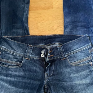 Mörkblå jeans från Pepe Jeans - Snygga mörkblå jeans från Pepe Jeans med klassisk femficksdesign, kontrastsömmar och broderad logga på bakfickan. Jeansen har raka ben och normal passform, tillverkade i slitstarkt denimtyg med lätt tvättad look. Perfekta för en avslappnad stil.