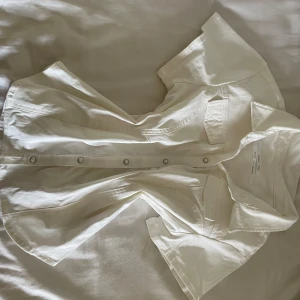 Vit kortärmad skjorta Silence + Noise - Snygg vit skjorta från Silence + Noise i storlek XL. Skjortan har korta ärmar, klassisk krage och knäppning framtill med stilrena knappar. Perfekt för en clean och fräsch look. Tillverkad i mjukt bomullstyg som känns skönt mot huden. Aldrig använts. Den är storlek XL men jag har vanligtvis storlek M eller S och den sitter som en M.