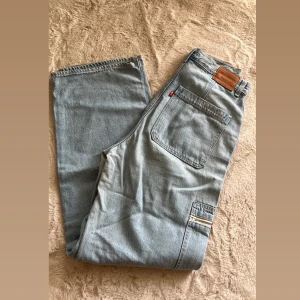 Levi's ljusblå cargopants jeans - Ljusblåa cargopants från Levi's med raka ben och coola fickor med dragkedja på sidorna. Klassisk jeanslook med Levi's läderpatch bak och röd etikett. Tillverkade i slitstarkt bomullsjeansmaterial, perfekt för en avslappnad streetstil