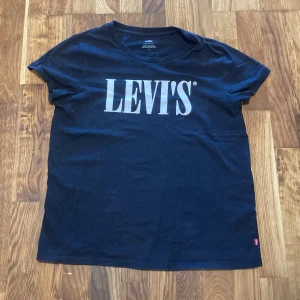 Svart Levi's t-shirt med logga - Svart t-shirt från Levi's i bomull med stor vit logga framtill. Klassisk rund halsringning och korta ärmar. Perfekt för en chill och stilren look.