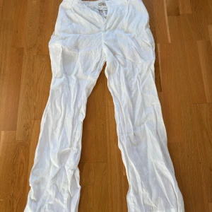 Vita linnebyxor i rak modell, S - Snygga och luftiga vita linnebyxor i rak passform. Byxorna har klassisk midja, bälteshällor och dragkedja framtill. Perfekta för varma dagar och ger en fräsch och stilren look. Tillverkade i 100% linne för maximal komfort.