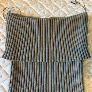 Ribbad grön stickad klänning - Supersnygg ribbad grön stickad topp med axelbandslös design. Klänningen har en tight passform och är perfekt för dig som gillar en stilren och modern look. Materialet är mjukt och följsamt, vilket gör den både bekväm och trendig.