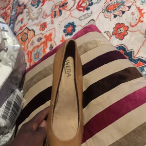 Beiga pumps från Wera och svarta boots - Säljer ett par klassiska beiga pumps från Wera i skinn med rund tå och smal klack. Dessutom ett par svarta boots med spetsig tå, låg klack och croco-mönstrad yta i glansigt material. Perfekta för dig som gillar stilrena och trendiga skor.