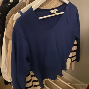 Mörkblå v-ringad tröja från COS - Mörkblå v-ringad tröja från COS i mjukt material. Tröjan har lång ärm och en klassisk, stilren design som passar perfekt till jeans eller kjol. Enkel och snygg modell med normal passform.