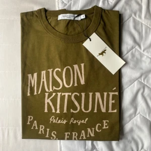 Maison Kitsune T-shirt - Säljer nu olivgröna Maison Kitsune tishor i storlek M |Helt nya och inplastade | Skick: 10/10, aldrig använda. Etiketten sitter kvar. Skriv gärna till mig ifall du är intresserad av fler bilder osv :)