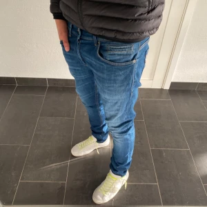 Dondup George jeans - Säljer ett par blå skinny fit jeans från dondup i storlek 34. Modellen är George. Jeansen har klassisk femficksdesign, smal passform och är tillverkade i mjukt denimtyg. Perfekta för dig som gillar en tajt och modern look.