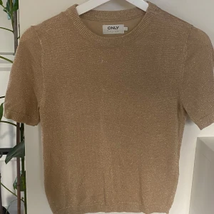 Glittrig beige topp från ONLY!  - Säljer en glittrig beige topp från ONLY i storlek S. Toppen har korta ärmar, rund halsringning! Ny och oanvänd! 