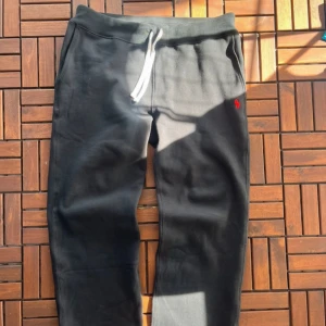  mjukisbyxor, Polo Ralph Lauren - Svarta mjukisbyxor från Polo Ralph Lauren med vit dragsko i midjan och röd broderad logga på ena benet. Byxorna har en avslappnad passform och är tillverkade i mjuk bomull, perfekta för chill dagar. Klassisk look med elastisk midja och raka ben. Orginalpris 1300 helt nya