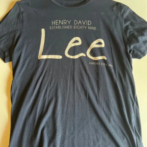 blå Lee t-shirt med tryck - Snygg mörkblå t-shirt från Lee med stort vitt tryck framtill där det står 'Henry David Established Eighty Nine' och 'Kansas City, MO'. Klassisk rund hals och korta ärmar. Tillverkad i mjuk bomull för en skön känsla.