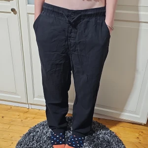 Svarta linnebyxor från H&M - Svarta linnebyxor från H&M med avslappnad passform och resår i midjan. Byxorna har raka ben, sidfickor och en bakficka. Perfekta för en chill och stilren look. Materialet är lätt och luftigt linne.